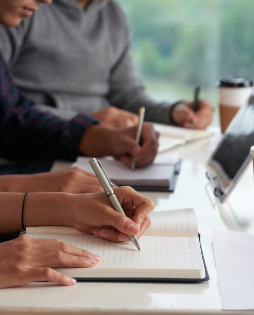 three students taking test on pen and paper